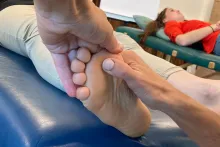 Ein Bild zeigt zwei Hände, die eine Fußsohle massieren.